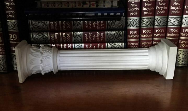 Photo of plaster cast sculpture of Greek half column on a wooden bookshelf with old dictionaries
