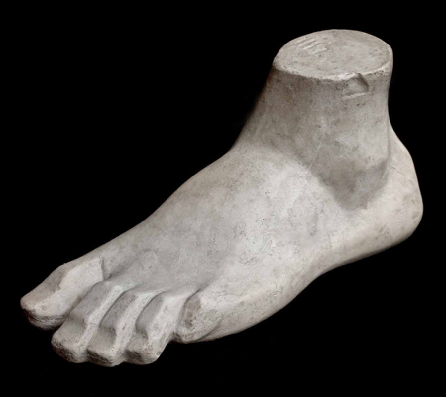 Photo of plaster cast sculpture of blocked foot on a black background