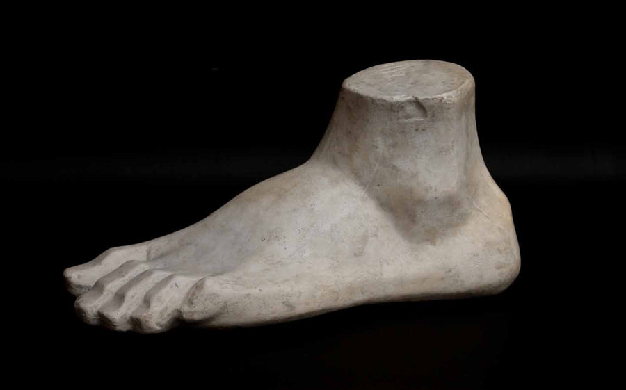 Photo of plaster cast sculpture of blocked foot on a black background