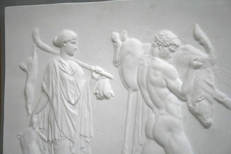 cropped photo of relief plaster cast with two figures walking towards the right