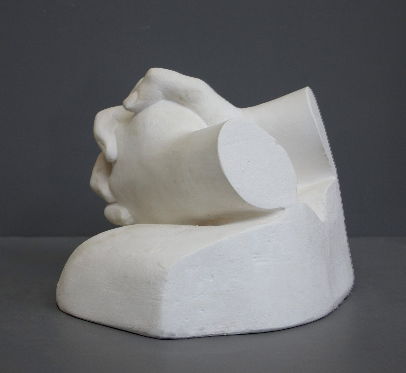 photo on gray background of plaster cast sculpture of Joan of Arc&#39;s hands clasped on top of a portion of her knees