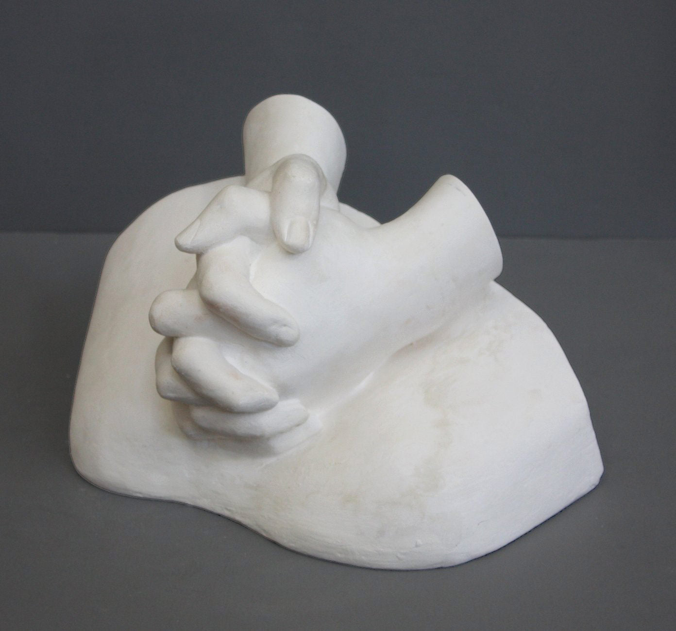 photo on gray background of plaster cast sculpture of Joan of Arc&#39;s hands clasped on top of a portion of her knees
