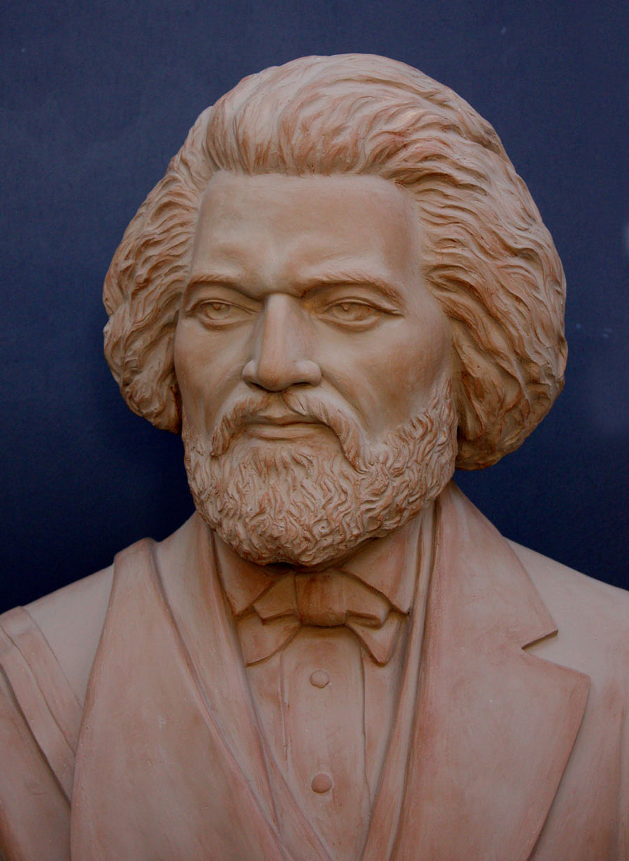 photo detail of terracotta-colored plaster cast sculpture of bust of Frederick Douglass with beard and in suit coat with toga over one shoulder on dark gray background