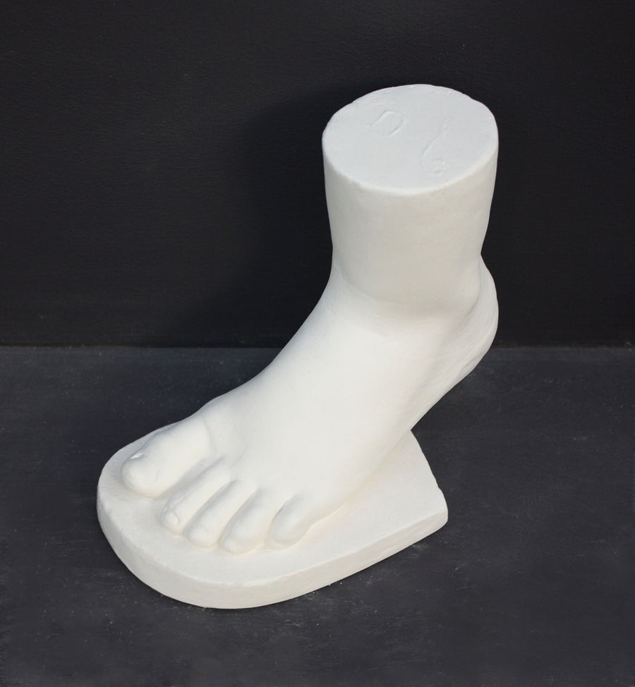 photo of white plaster cast sculpture of child foot against gray background