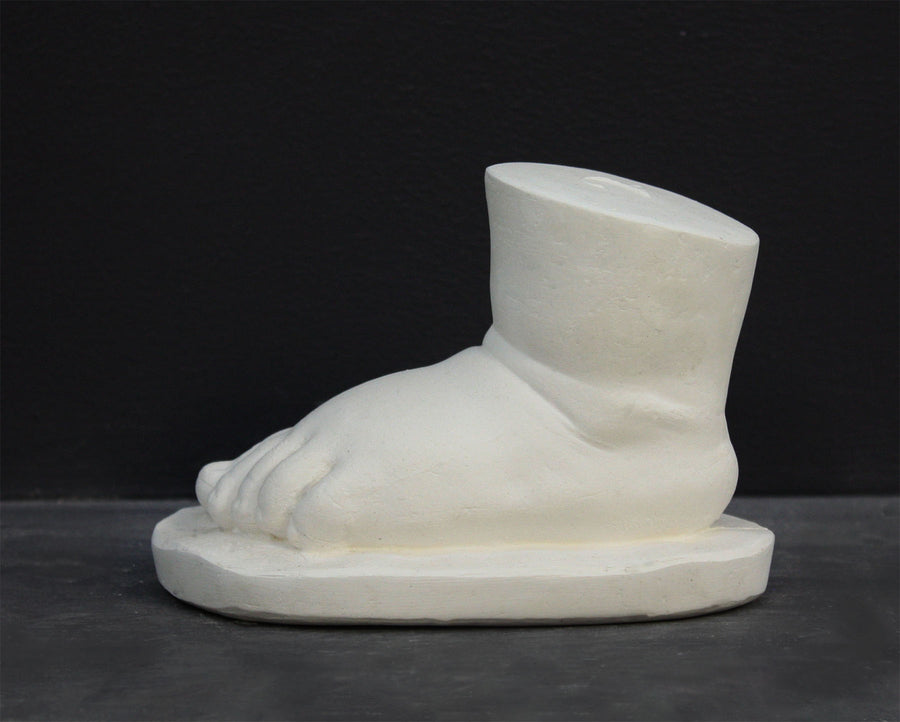 photo of white plaster cast sculpture of baby foot against gray background