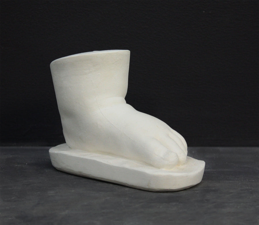 photo of white plaster cast sculpture of baby foot against gray background