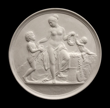 photo with black background of plaster cast relief sculpture of mostly nude female figure with two children and flowers and wreaths