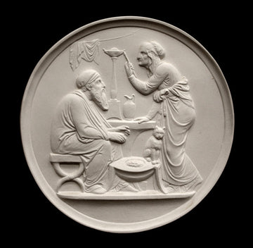 photo of off-white plaster cast relief sculpture of elderly male and female figures at a table and a cat against black background