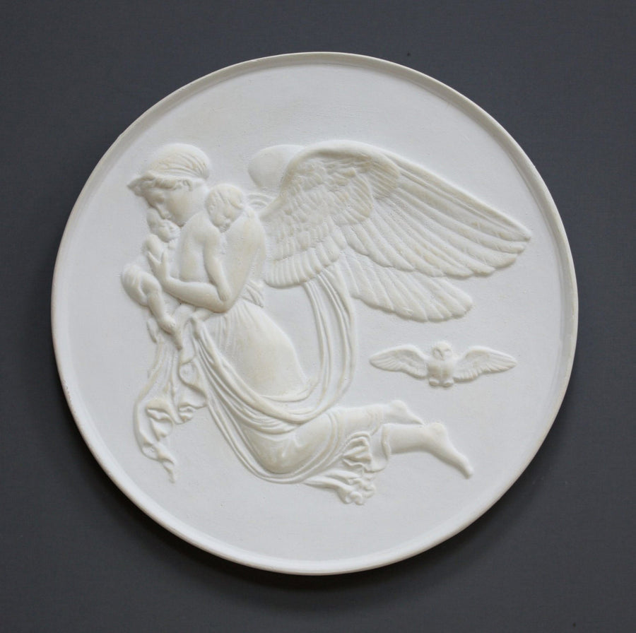 photo of plaster cast relief of woman with wings flying with two children nestled against her and an owl flying on a dark background