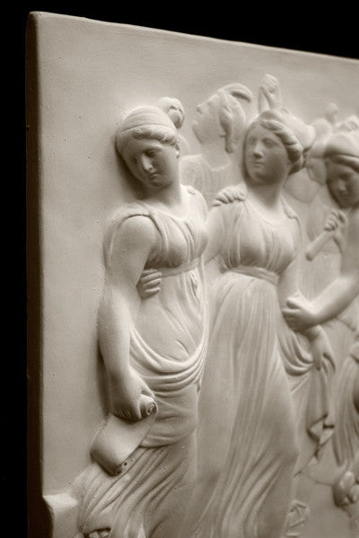 Photo with black background of plaster cast sculpture relief of females dancing