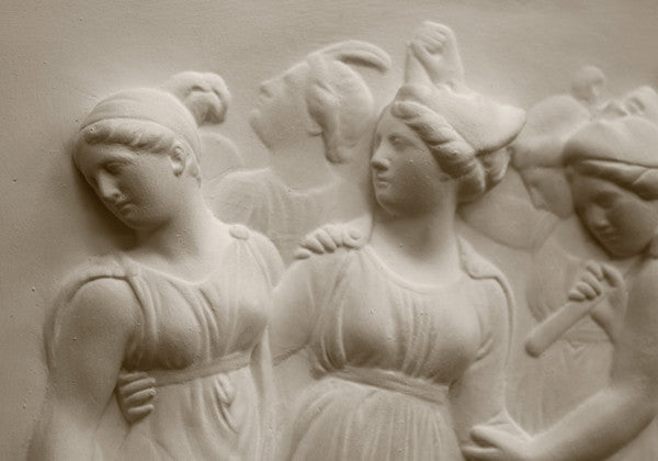 Photo with black background of plaster cast sculpture relief of females dancing