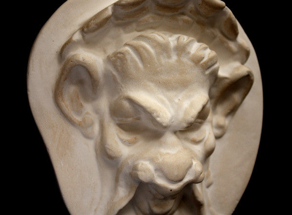 Photo of a cropped plaster sculpture of a Faun Head on a black background
