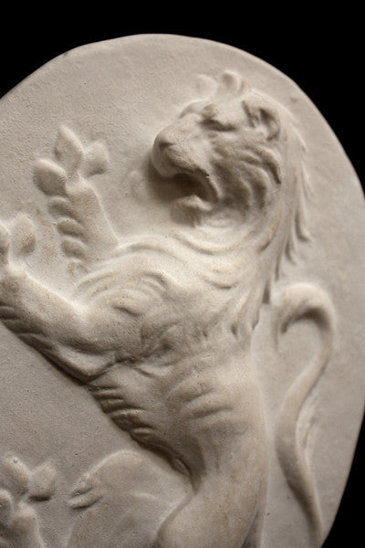 Photo with black background of plaster cast sculpture relief of lion on hind legs