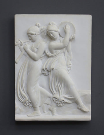 Photo with black background of plaster cast sculpture relief of females playing instruments