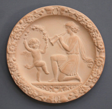 photo with gray background of plaster cast of small relief with a dancing child and a young man playing two horns
