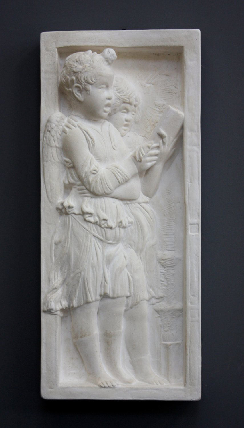 photo of plaster cast relief sculpture with two angels singing from a book on a gray background