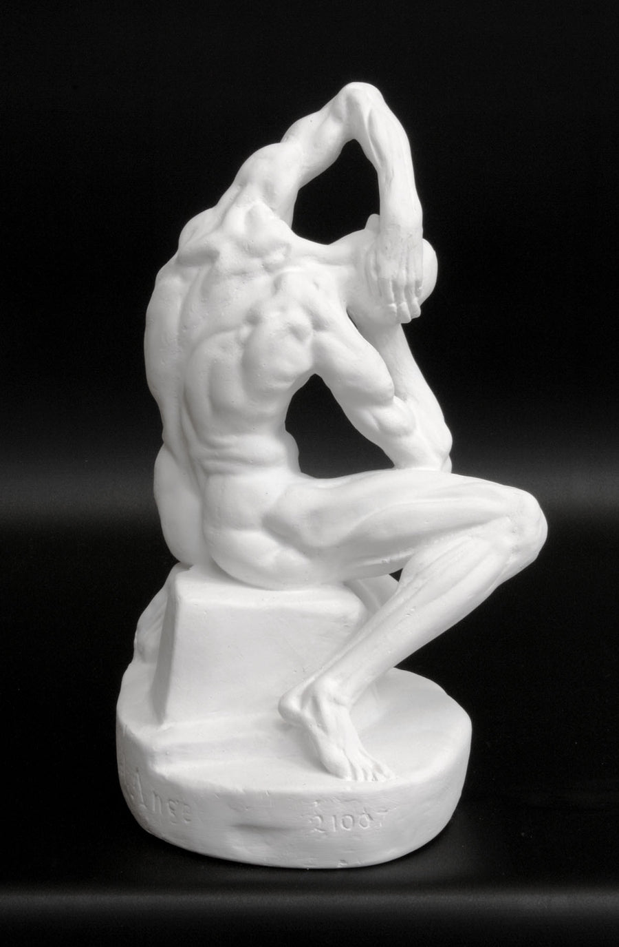 Photo of plaster cast sculpture of flayed man kneeling with hands on head on black background