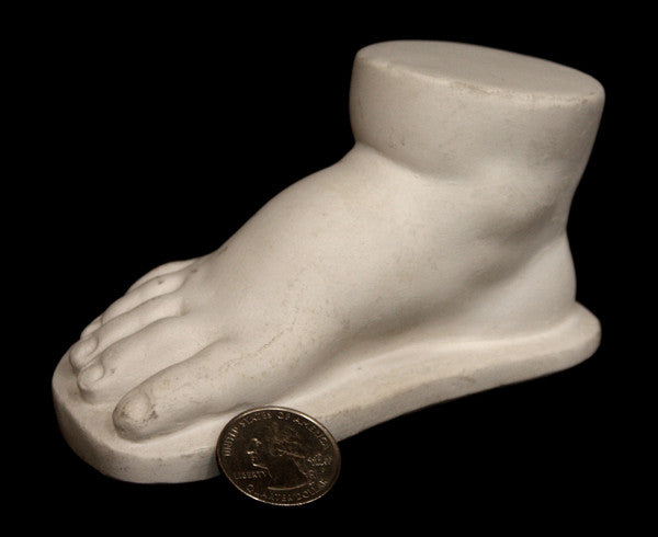 photo of off-white plaster cast sculpture of baby foot against black background