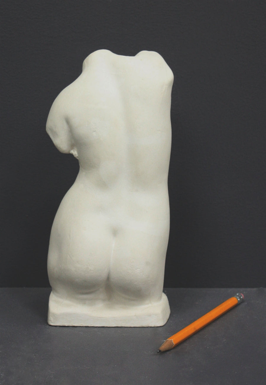 photo of off-white plaster cast sculpture of female torso and yellow pencil beside it against dark gray background