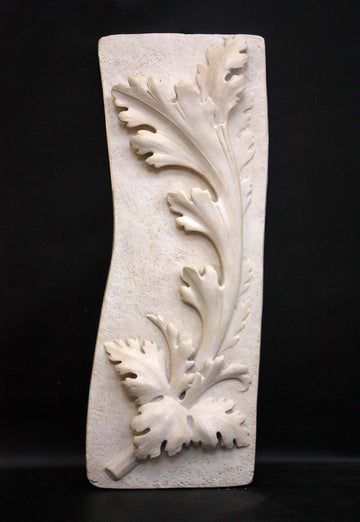 photo of off-white plaster cast relief sculpture of acanthus leaf against black background