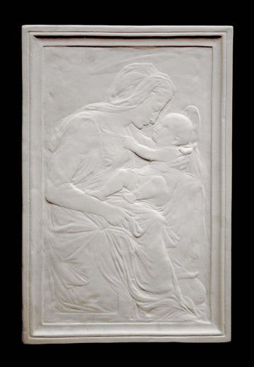 photo of plaster cast sculpture relief of the Madonna holding baby Jesus on her lap on black background