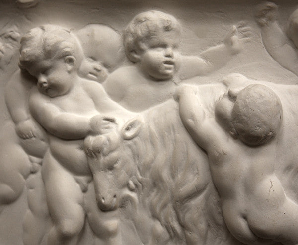 closeup photo of plaster cast relief sculpture of several putti around a goat celebrating the god Bacchus