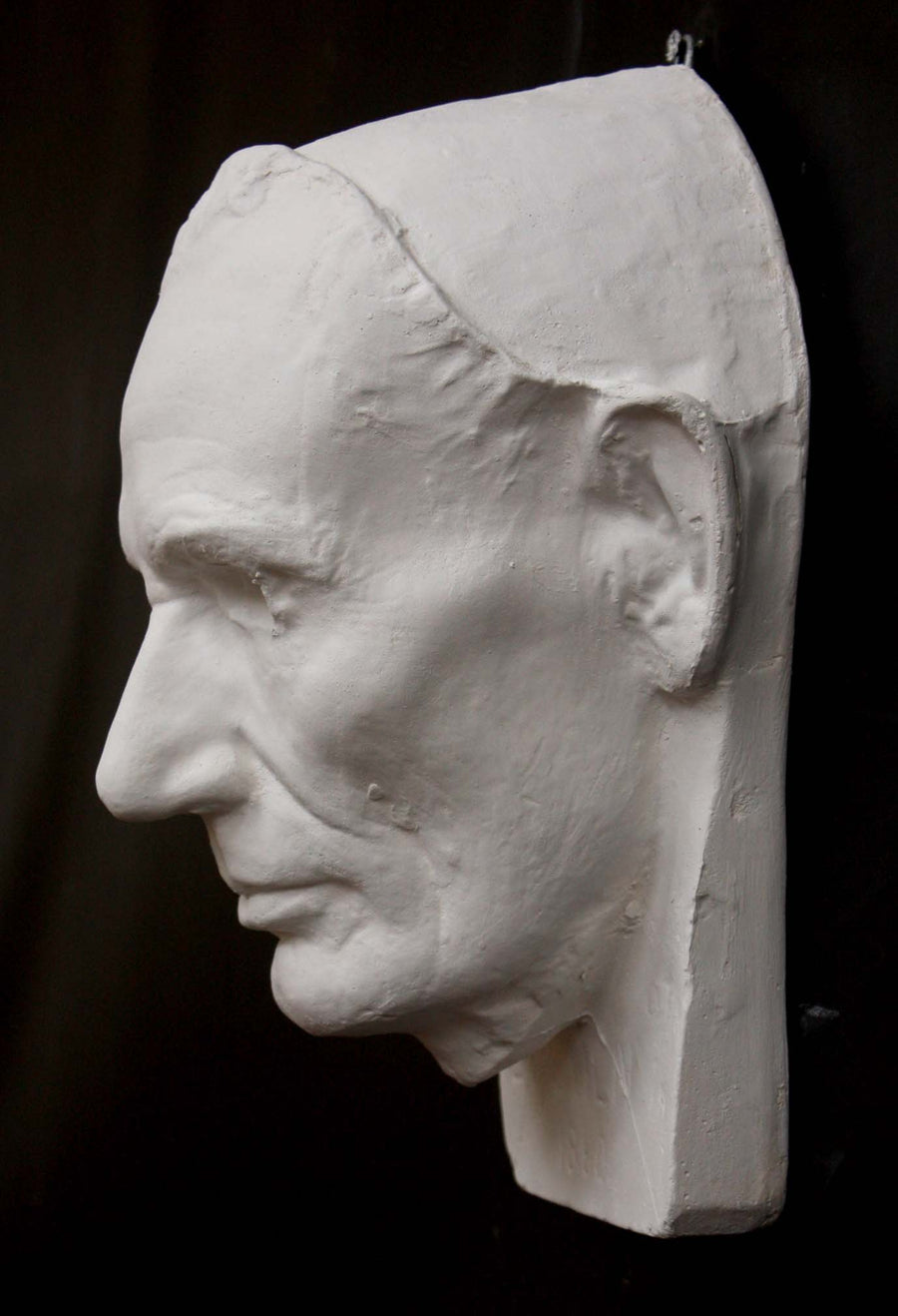 Photo of plaster cast sculpture of life mask of Abraham Lincoln from a side view on a black background