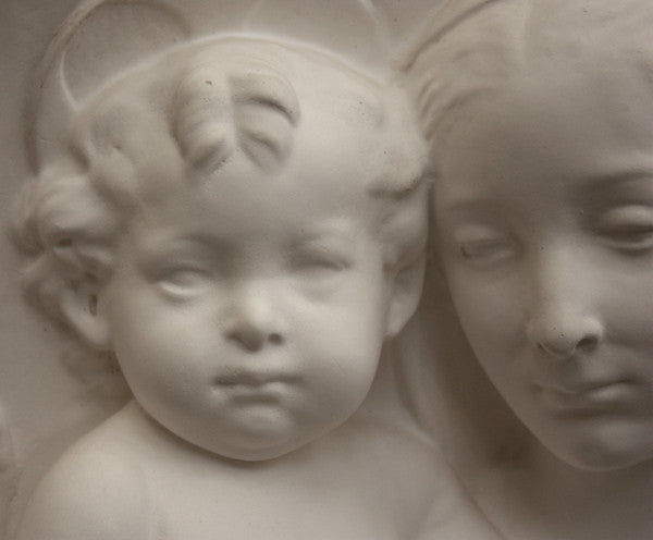 closeup photo of plaster cast sculpture relief of the Madonna holding baby Jesus