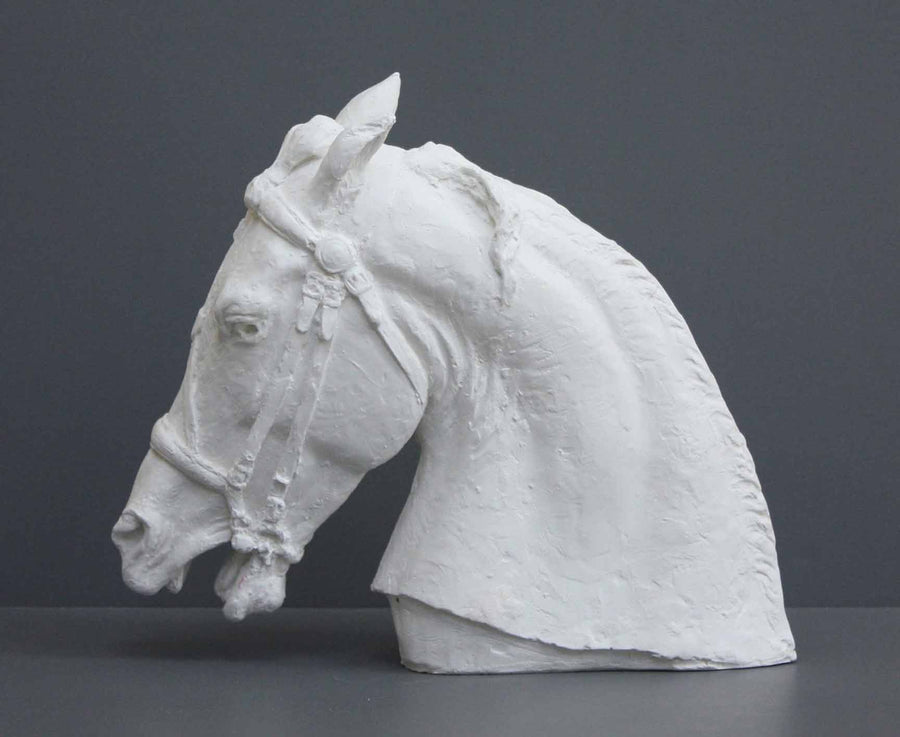 photo of plaster cast of horse head with bridle on a gray background