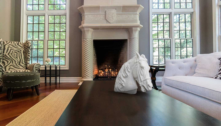 Photo of ornate living room with fireplace and columns with a plaster sculpture cast of a horse with bridal on a wooden coffee table in the foreground