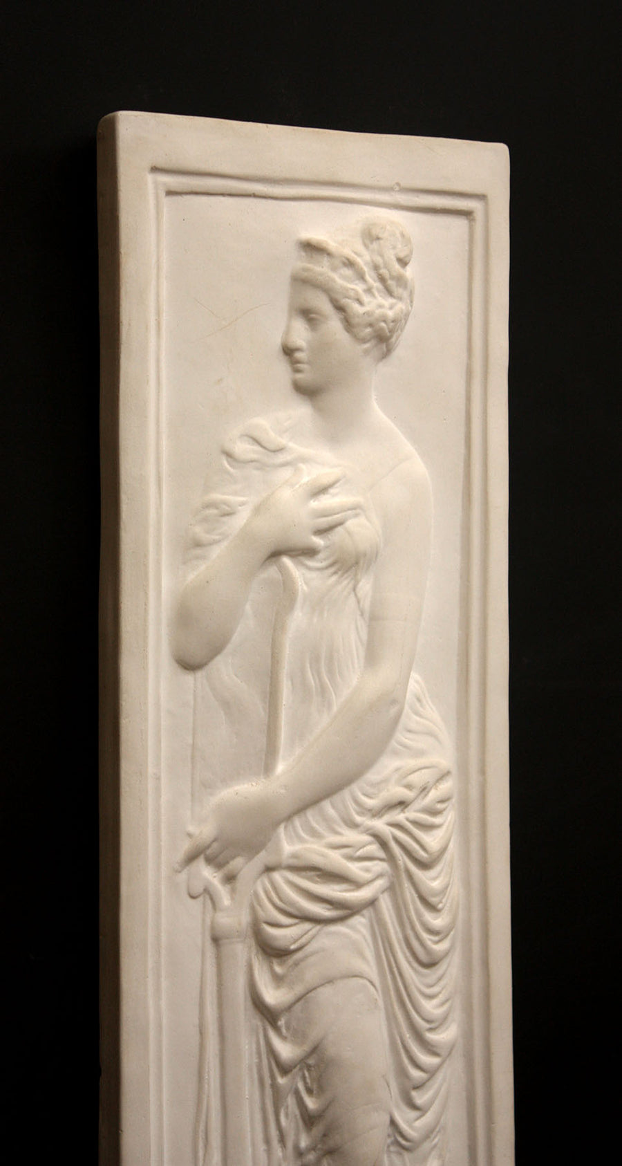 photo of white plaster cast relief sculpture of female figure in drapery
