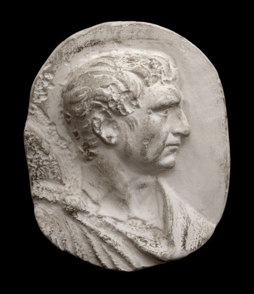 photo of plaster cast sculpture relief of male head and top of toga with a black background