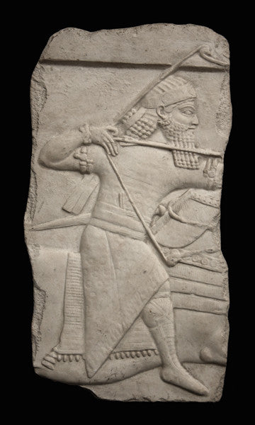 photo of plaster cast relief sculpture of King Ashurbanipal on horseback (only midsection of horse visible) and aiming an arrow in front of him on a black background