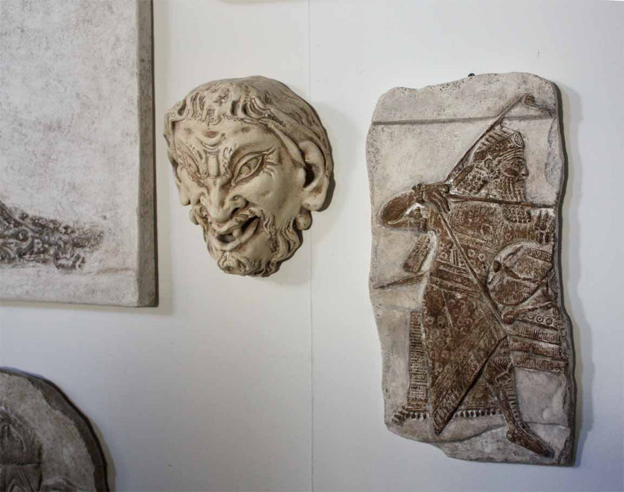 Photo of plaster cast sculpture of ancient sculpture relief and plaster casts of other sculptures on a white gallery wall