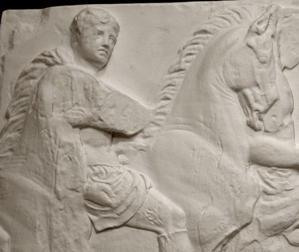 closeup photo of off-white plaster cast relief sculpture of three men on horseback from Parthenon against black background
