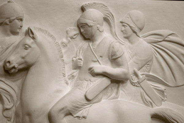 closeup photo of plaster cast relief sculpture showing three men on horses against black background