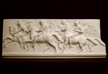 photo of plaster cast relief sculpture of men on horses against black background