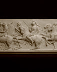 photo of plaster cast relief sculpture of men on horses against black background