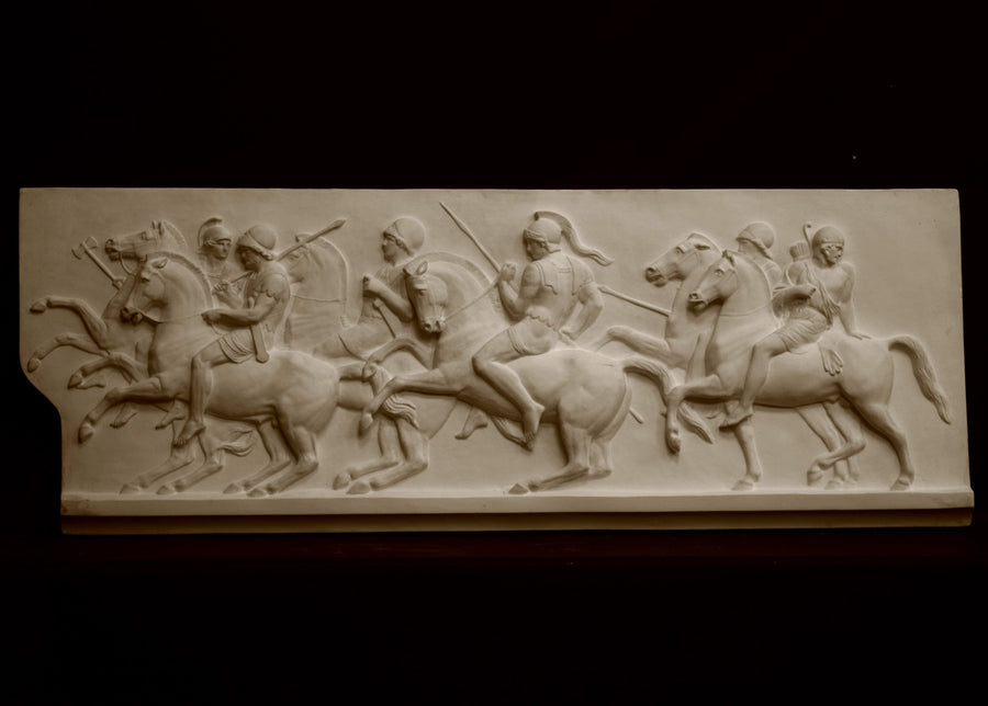 photo of plaster cast relief sculpture of men on horses against black background