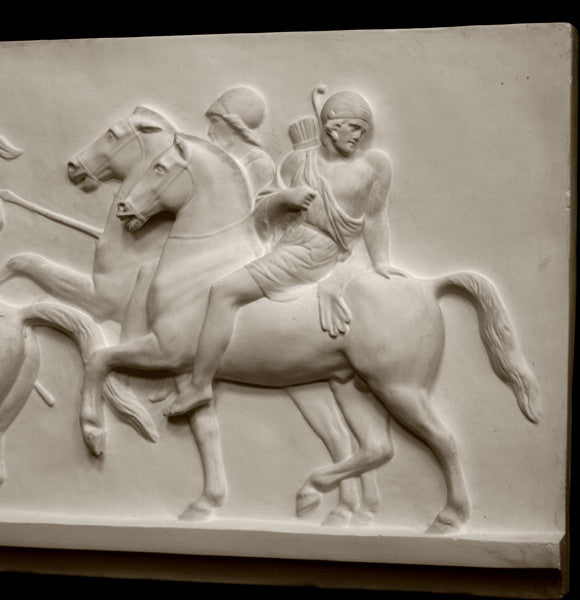 closeup photo of plaster cast relief sculpture showing two men on horses against black background