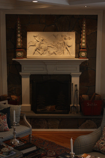 photo of plaster cast relief of men, some with armor, horses, and a dog over a fireplace with a stone wall