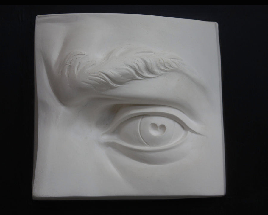 photo with black background of plaster cast of sculpted portion of face with left eye