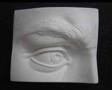 Photo of plaster cast sculpture of portion of face with right eye from Michelangelo's David statue on a black background