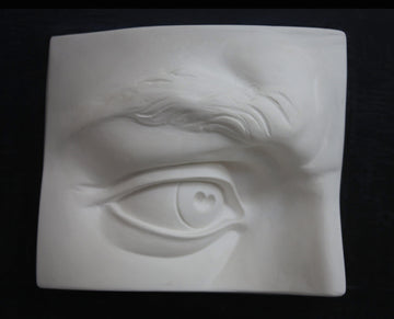 photo with black background of plaster cast of sculpted portion of face with right eye