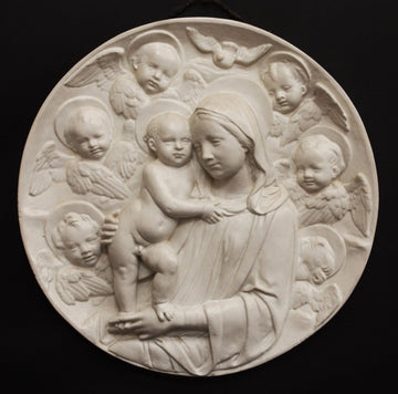 photo with black background of plaster cast relief of Madonna holding the Baby Jesus who's standing on her lap, and Angels encircling the round plaque