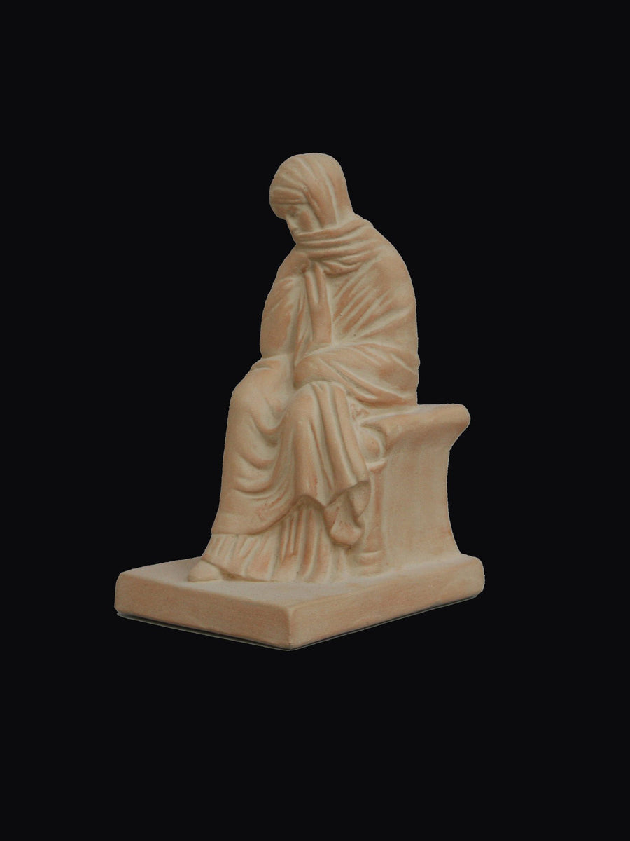 photo with a black background of a plaster cast sculpture of a seated female figurine painted terra cotta