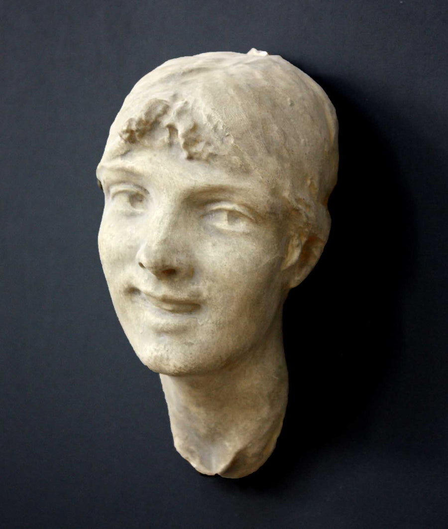 photo of antique plaster cast sculpture of front half of woman's head and neck against black background