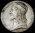 photo of off-white plaster cast relief sculpture of small medallion of male portrait in profile and text around the edge on black background