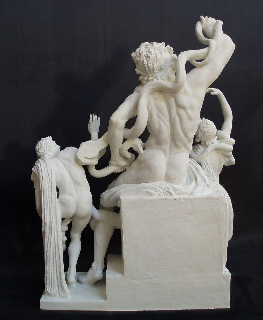 photo with black background of plaster cast sculpture from the back of partially nude male figure, namely Laocoon, and two nude young men being attacked by serpents which twist in and out of the three figures