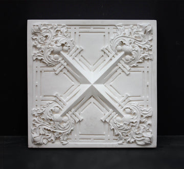 photo of white plaster cast of architectural ornament with geometric lines and leaf patterns against black background